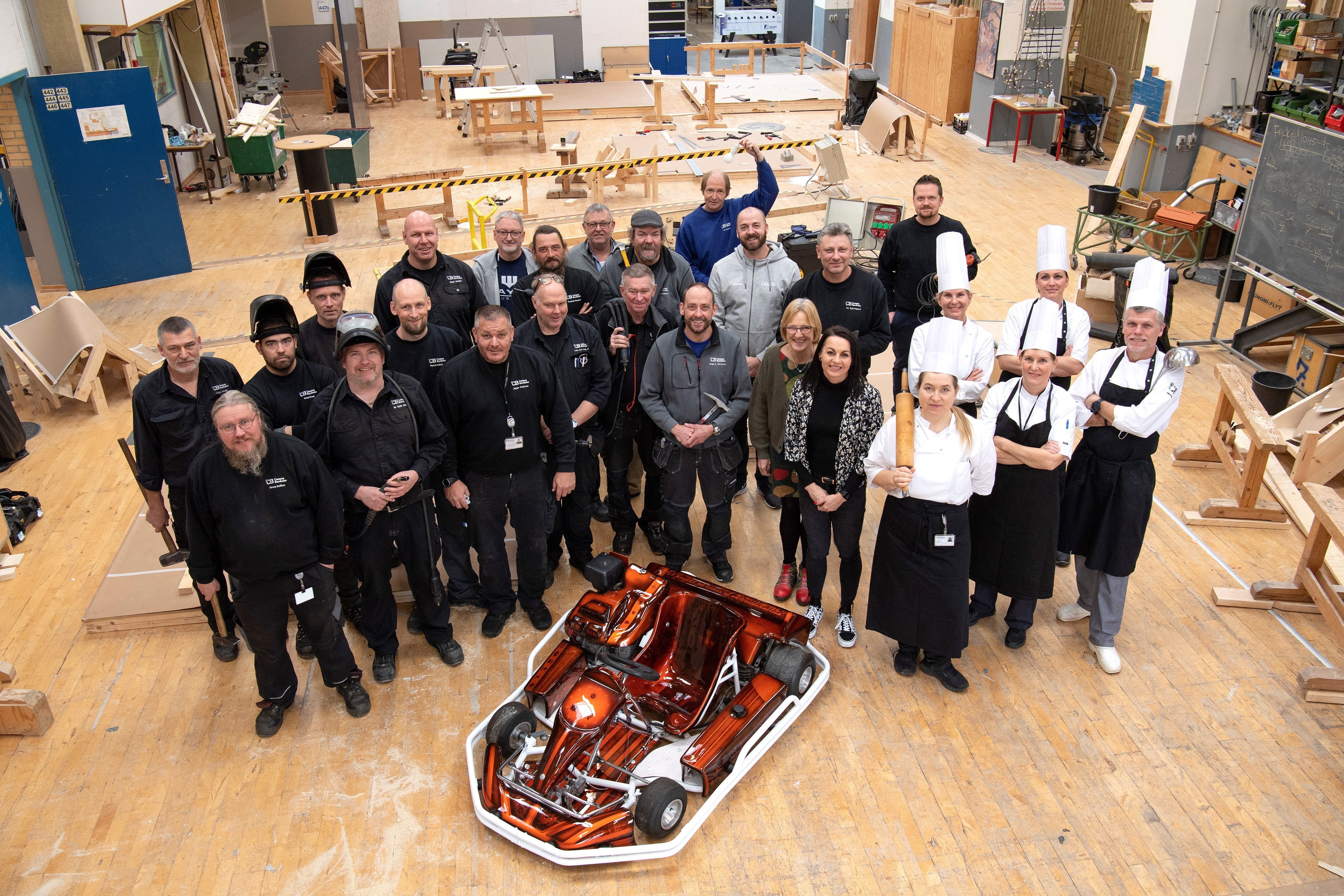 Gruppe med omkring 30 faglærere i arbejdstøj og med værktøj i hænderne